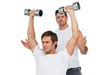 Male trainer assisting man with dumbbells