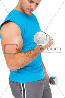 Mid section of a fit young man exercising with dumbbells