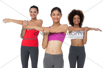 Portrait of three sporty young women stretching hands