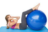 Side view of a fit woman exercising with fitness ball