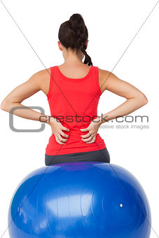 Rear view of a fit young woman sitting on exercise ball