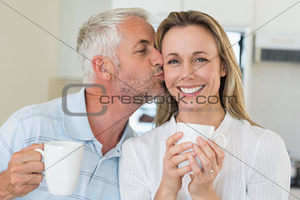Casual man giving his smiling partner a kiss on the cheek
