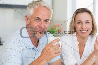 Happy couple having coffee together looking at camera