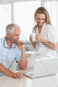 Cheerful couple using laptop together at the counter