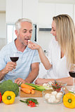 Affectionate couple preparing dinner together and drinking red wine