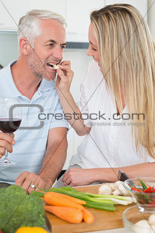 Affectionate couple preparing dinner together and drinking red wine