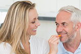 Happy woman feeding her partner vegetable piece