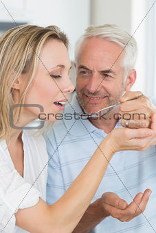 Happy man feeding his partner a spoon of the dinner