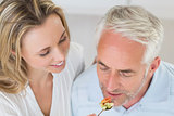 Happy woman feeding her partner a spoon of vegetables