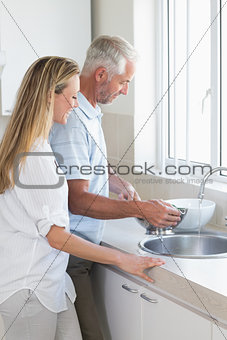 Couple rinsing vegetables in colander