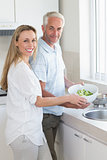 Couple rinsing vegetables at the sink