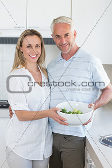 Couple holding bowl of broccoli smiling at camera