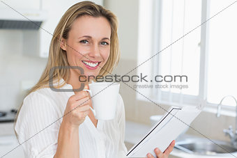 Smiling woman holding mug and newspaper
