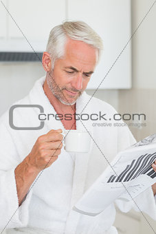 Happy man reading newspaper at breakfast in a bathrobe