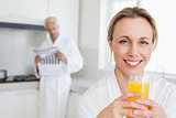Happy woman drinking orange juice in bathrobe