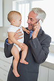 Smiling businessman holding his baby in the morning before work