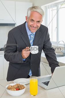 Happy businessman using laptop in the morning before work