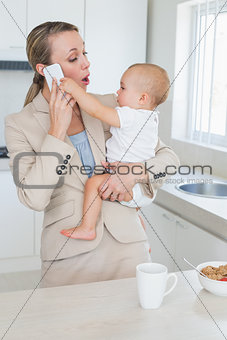 Happy businesswoman holding her baby talking on the phone
