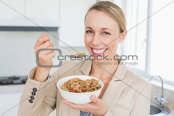 Happy businesswoman eating cereal before work in the morning