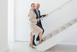 Smiling estate agent showing stairs to potential buyer