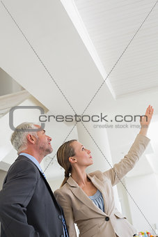 Smiling estate agent showing ceiling to potential buyer