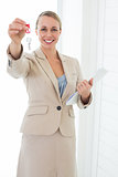 Smiling estate agent showing keys to camera