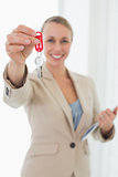 Smiling estate agent showing keys to camera