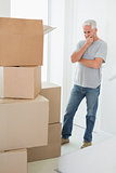 Thoughtful man looking at cardboard moving boxes