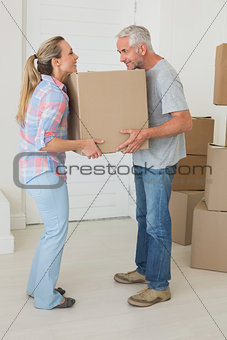 Happy couple carrying cardboard moving boxes