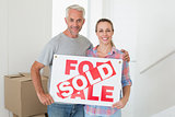 Happy couple standing and holding sold sign