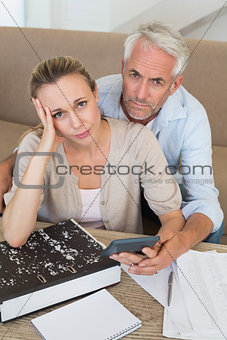 Serious couple calculating their bills at the couch