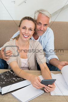 Smiling couple calculating their bills at the couch
