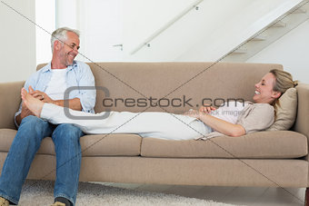 Caring man giving his partner a foot rub on the couch