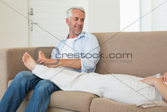 Caring man giving his partner a foot rub on the couch