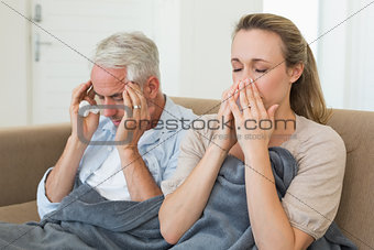 Sick couple sitting on the couch under a blanket