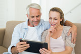 Happy couple using tablet pc together on the couch