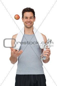 Smiling fit young man with apple and water bottle