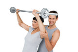 Personal trainer helping woman with weight lifting bar