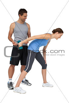 Male trainer assisting woman with dumbbell
