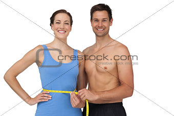Fit young man measuring womans waist