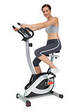 Side view of a beautiful young woman on stationary bike
