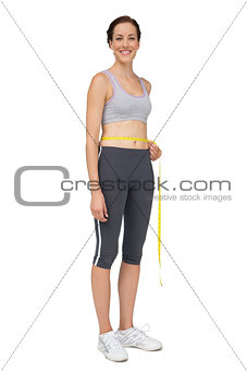 Full length portrait of a fit woman measuring waist