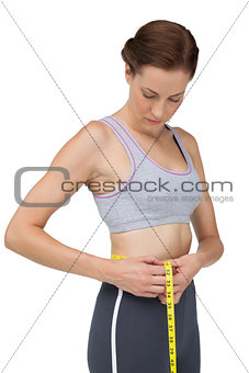 Portrait of a fit woman measuring waist