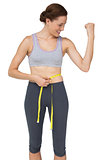 Fit woman measuring waist while flexing muscles