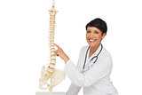 Smiling female doctor pointing at skeleton model