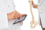 Mid section of doctors with digital table and skeleton model