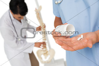 Mid section of doctors with pills and skeleton model