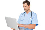 Concentrated male surgeon using laptop