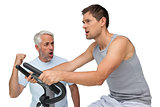 Determined young man on stationary bike with trainer