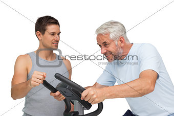 Determined mature man on stationary bike with trainer